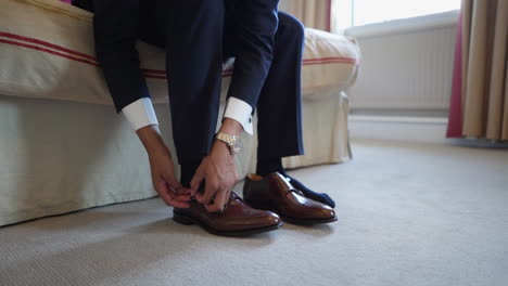 A-suited-man-is-putting-on-his-shoes-sitting-in-a-room