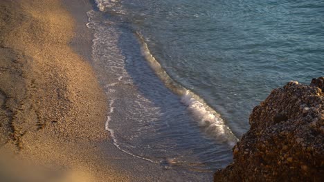 Looking-down-on-golden-sand-on-beach-with-calm-waves-breaking