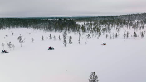 Gruppe-Von-Menschen,-Die-An-Einem-Wintertag-In-Der-Winterlichen-Landschaft-Rund-Um-Die-Stadt-Muonio-In-Lappland,-Finnland,-Mit-Dem-Schneemobil-Unterwegs-Sind