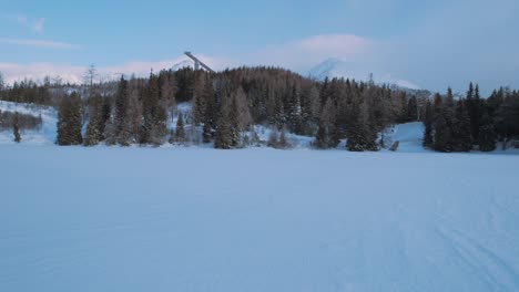 Luftdrohnenansicht-Der-Schneebedeckten-Bergskilandschaft,-Fliegen-über-Tannenwald-Zeigt-Skisprungschanzenstruktur,-Bewölkter-Tag,-Hohe-Tatra-Slowakei,-Vorwärtswagen-Herein
