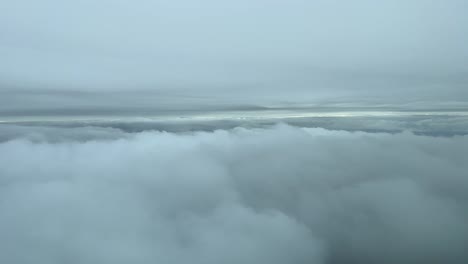 View-from-a-jet-cockpit-flying-between-layers-of-clouds-in-a-cold-winter-day,-near-the-seashore