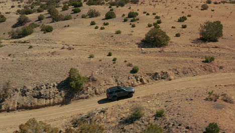Aerial-tracking-with-adventure-overland-SUV-driving-on-dirt-road-in-desert