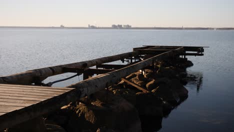 A-dynamic-shot-of-a-broken-jetty-moving-from-the-footpath-towards-the-open-water-to-the-horizon