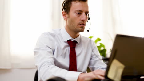 Businessman-office-worker-taking-note-with-pen-while-talking-in-video-conference-using-headphone-in-call-center-customer-care