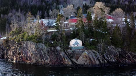 Stunning-View-Of-Arctic-Dome-Igloo-At-The-Edge-Of-Rocky-Cliffs-By-The-Shore-In-Norway