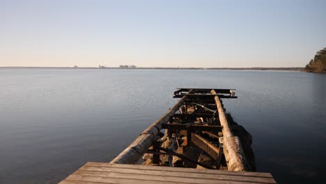 A-dynamic-shot-of-a-broken-jetty-moving-upwards-from-the-footpath-towards-the-open-water-to-the-horizon