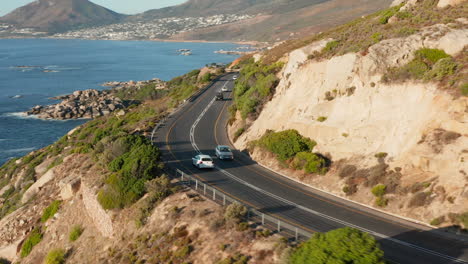 Cars-Driving-In-Hillside-Road-Overlooking-Beautiful-Seaside-Scenery-In-Cape-Town,-South-Africa---aerial-shot