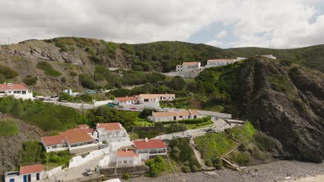 Aerial-shot-zooming-out-of-white-villas-with-orange-rooftops-on-rugged-hills-along-a-beautiful-beach