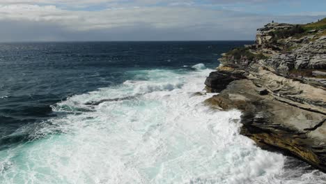 Rocky-coast-near-Bondi-beach-with-stormy-waves-crashing-on-cliff-in-Australia