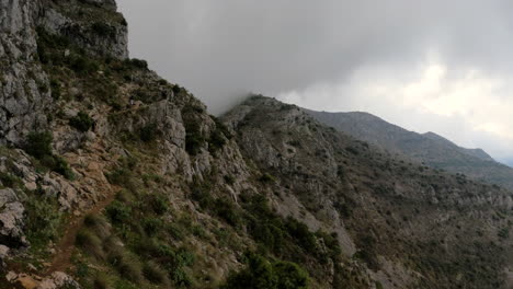 4K-Shot-of-people-climbing-on-a-mountain-with-large-rocks-on-a-cloudy-day-in-Spain