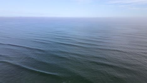 Pullback-drone-shot-of-the-Atlantic-Ocean-under-a-clear,-blue-sky