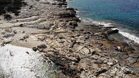 Aerial-View-Of-Rocky-Shore-At-Paralia-Emplisi-Beach-In-Greece-During-Summer---drone-shot