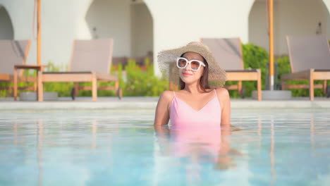 A-pretty-young-woman-leans-back-on-her-elbows-in-the-shallow-water-of-a-resort-swimming-pool