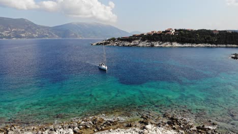 Luftbahnansicht-Des-Segelbootes,-Das-Im-Kristallklaren-Wasser-Von-Paralia-Emplisi-In-Griechenland-Schwimmt