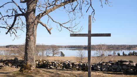 Wide-shot-of-Christian-catholic-cross-in-field-during-day-with-water-pond-in-the-background