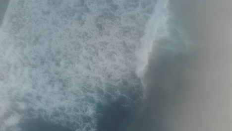 A-top-down-drone-shot-of-waves-crashing-by-in-the-fog-on-the-Oregon-Coast,-moody-and-relaxing-ocean