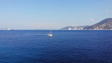 Paralia-Emplisi-Beach-Waters-Being-Sailed-By-Boats-And-A-Mountain-Side-Peeking-Through--Lateral-Aerial-Shot