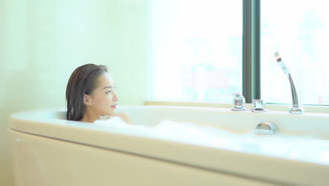 A-pretty-woman-relaxes-in-a-bubble-bath-as-she-looks-out-of-her-high-rise-window