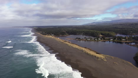 Garrison-lake-in-Port-Orford-at-the-Southern-Oregon-Coast,-divided-from-the-ocean-by-a-thin-strip-of-beach,-drone-shot-4k
