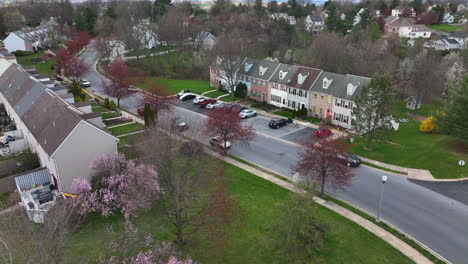 Rising-aerial-of-townhouse-homes-in-USA-town-community-during-spring-season-with-blooming-trees