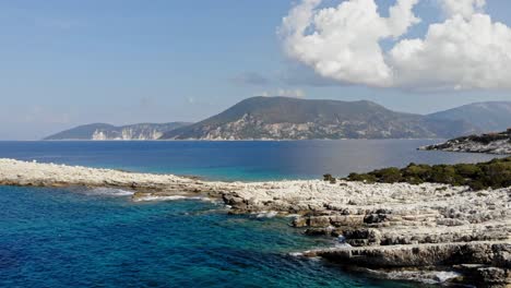 Rocky-Shore-With-Calm-Ocean-At-Paralia-Emplisi-And-Mountain-View-In-Kefalonia,-Ionian-Islands,-Greece