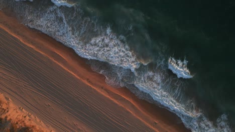 A-dynamic-high-angle-shot-of-the-shoreline-with-strong-waves-of-water-during-the-golden-hour