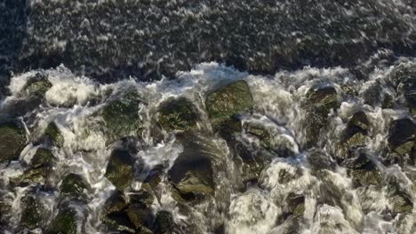 Fast-flowing-water-over-rocks-in-a-river-top-down-shot