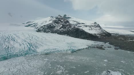Eisiger-Gletschersee-Durch-Schneebedeckte-Berge-In-Der-Winterlichen-Isländischen-Landschaft,-Aus-Der-Luft
