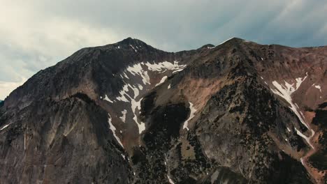 Drone-Footage-Of-Large-Alpine-Mountain-Summit-Covered-In-Melted-Snow