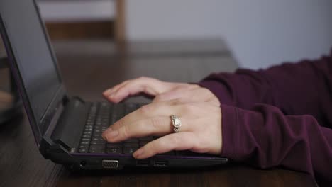 Focused-Female-Hands-With-A-Ring,-Typing-On-Laptop-On-The-Dining-Table-At-Home