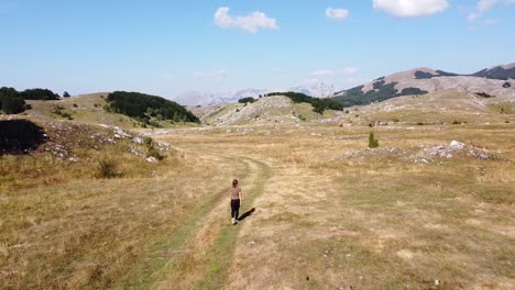 Mujer-Camina-En-El-Parque-Nacional-De-Durmitor,-Montenegro---Carretilla-Aérea-Hacia-Adelante