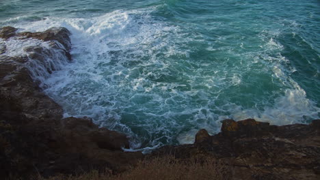 Turquoise-Blue-Waves-Crashing-Rocky-Shoreline-In-Perranporth,-Cornwall---static-shot