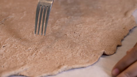 Pricking-Passover-bread-with-a-fork-so-it-doesn't-rise-during-baking---close-up-isolated