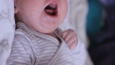 Closeup-portrait-of-cute-adorable-newborn-infant-baby-crying-in-bed-with-mouth-open,-static,-interior,-day