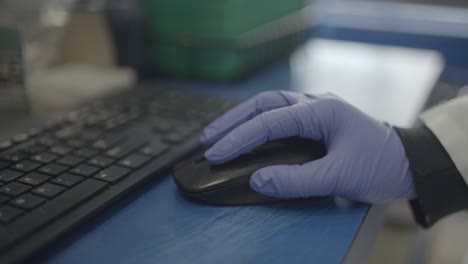 Scientist-in-lab-using-mouse-for-computer-research-with-gloves-on-hand