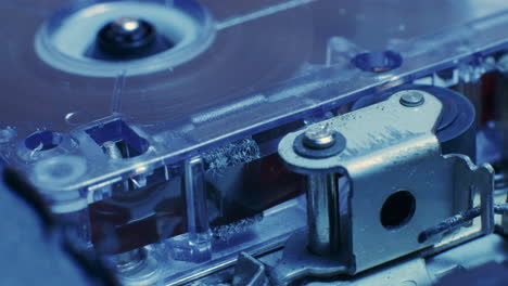 Nahaufnahme-Des-Bandbandes-Eines-Mikrokassettenrekorders,-Das-In-Kaltem-Blauem-Licht-Durch-Die-Kassette-Läuft
