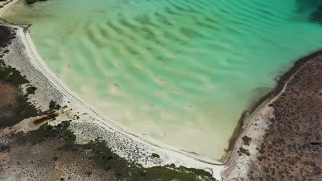 Filmische-Drohnenaufnahme-Des-Strandes-Von-Balandra,-Blick-Auf-Rote-Hügel,-Türkisfarbenes-Wasser,-Weiße-Sandstrände-Und-Berge