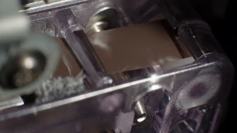 Extreme-Close-Up-Of-Microcassette-Recorder-Tape-Ribbon-Running-Through-Cassette