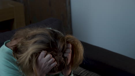 Depressed-woman-in-living-room-grabbing-her-hair-and-crying---close