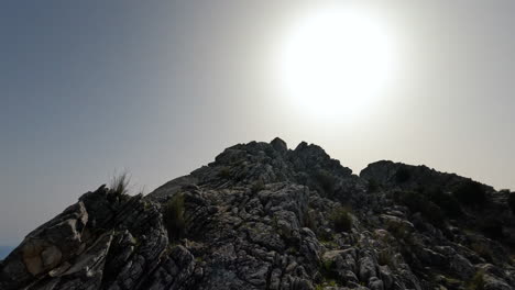 4k-Moving-shot-of-a-hiker-walking-up-a-rocky-mountainat-La-Concha,-Marbella,-Spain-on-a-sunny-day