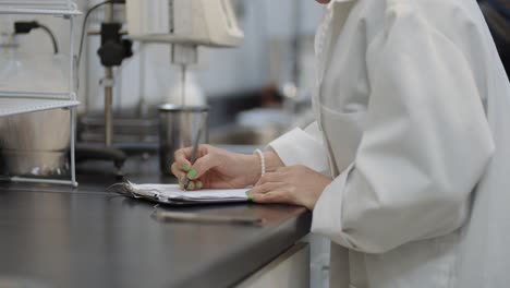White-coat-female-scientist-in-lab-taking-research-notes-on-experimentation