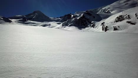 Acercar,-Enorme-Llanura-De-Nieve-En-Los-Alpes-Suizos,-Gran-Altitud,-Cielo-Azul-Y-Montañas