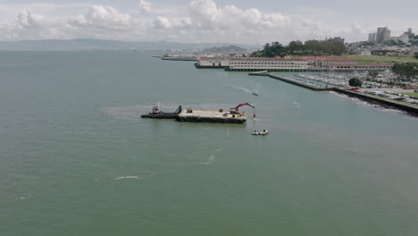 Slow-aerial-pedestal-shot-of-a-barge-pulling-things-out-of-the-water-in-San-Francisco,-California