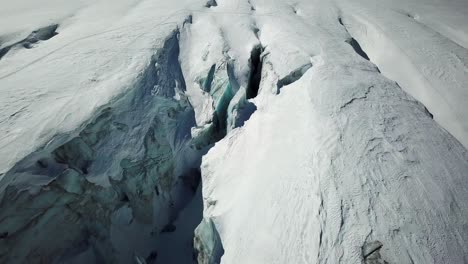 deep-and-dark-crevice-of-a-glacier-in-the-swiss-alps,-Saas-Fee,-drone-shot,-zoom-out