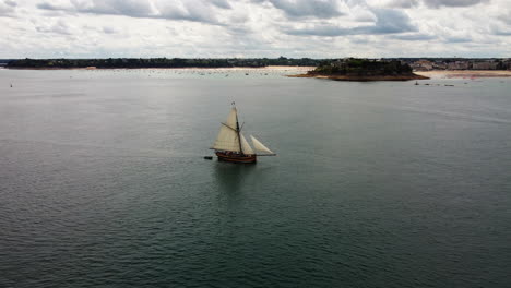 Aerial-pov-of-Le-Renard-wooden-corsair-ship-sailing-along-Saint-Malo-coast,-France