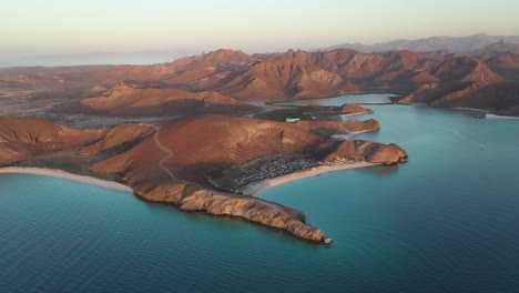 Cinematic-drone-shot-of-Balandra-Beach,-view-of-red-hills,-turquoise-waters,-white-sand-beaches,-and-mountains,-wide-rotating-slowly