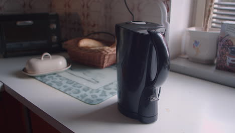 Hand-of-male-caucasian-is-turning-on-electric-kettle