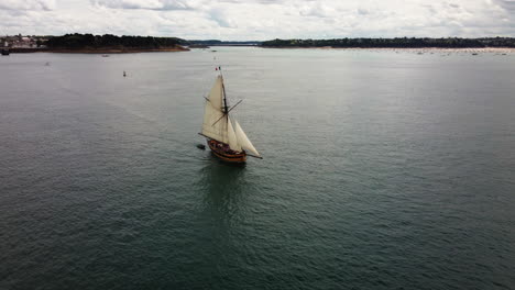 Aerial-view-of-Le-Renard-wooden-corsair-ship-sailing-along-Saint-Malo-coast,-France