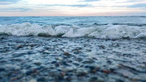 Low-angle-shot-of-crashing-waves-at-the-sea-shore-during-daytime-after-sunset,close-up