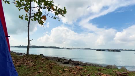 Camping-Tent-At-Jelutong-Campsite-With-Revealing-Shot-Of-Scenic-Pulau-Ubin-Island-On-A-Cloudy-Day,-In-Singapore